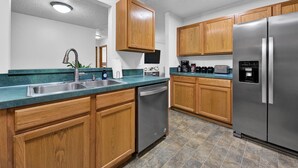 Una cocina moderna con armarios de madera, electrodomésticos de acero inoxidable y encimera verde.