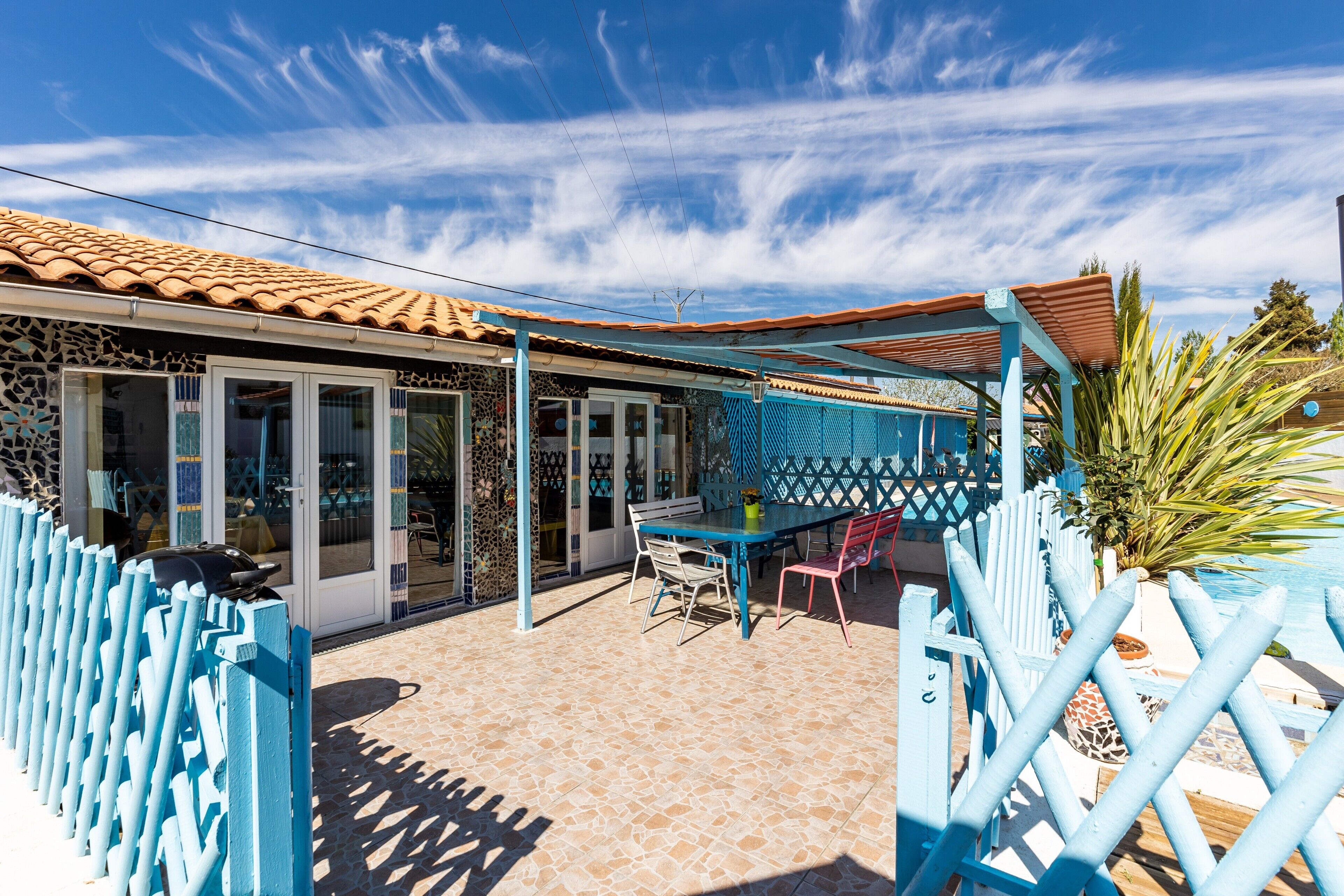 A patio area with a table and chairs, a covered seating area, and a pool.