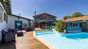 A pool area with a wooden deck, lounge chairs, and a building with a mural.