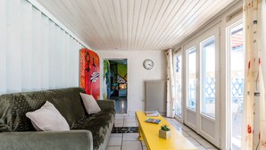 A living room with a sofa, a yellow table, and a clock on the wall.