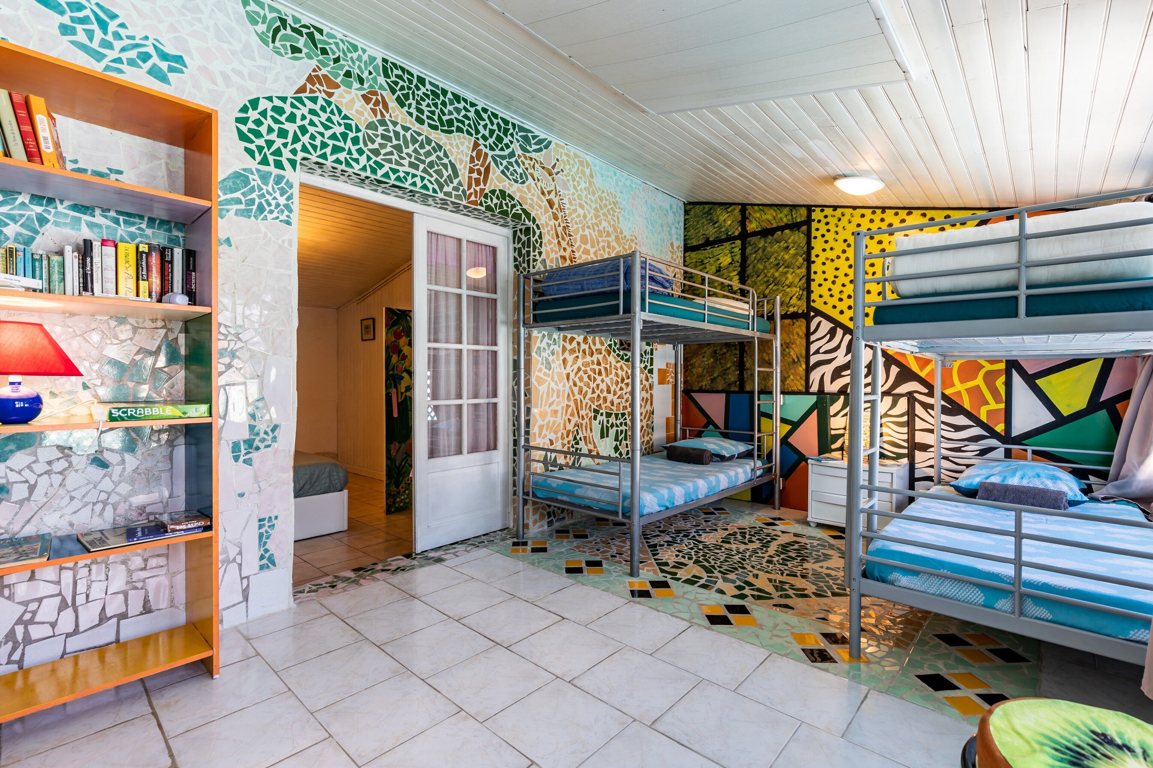 Une chambre avec des lits superposés, une bibliothèque et un sol à motifs.