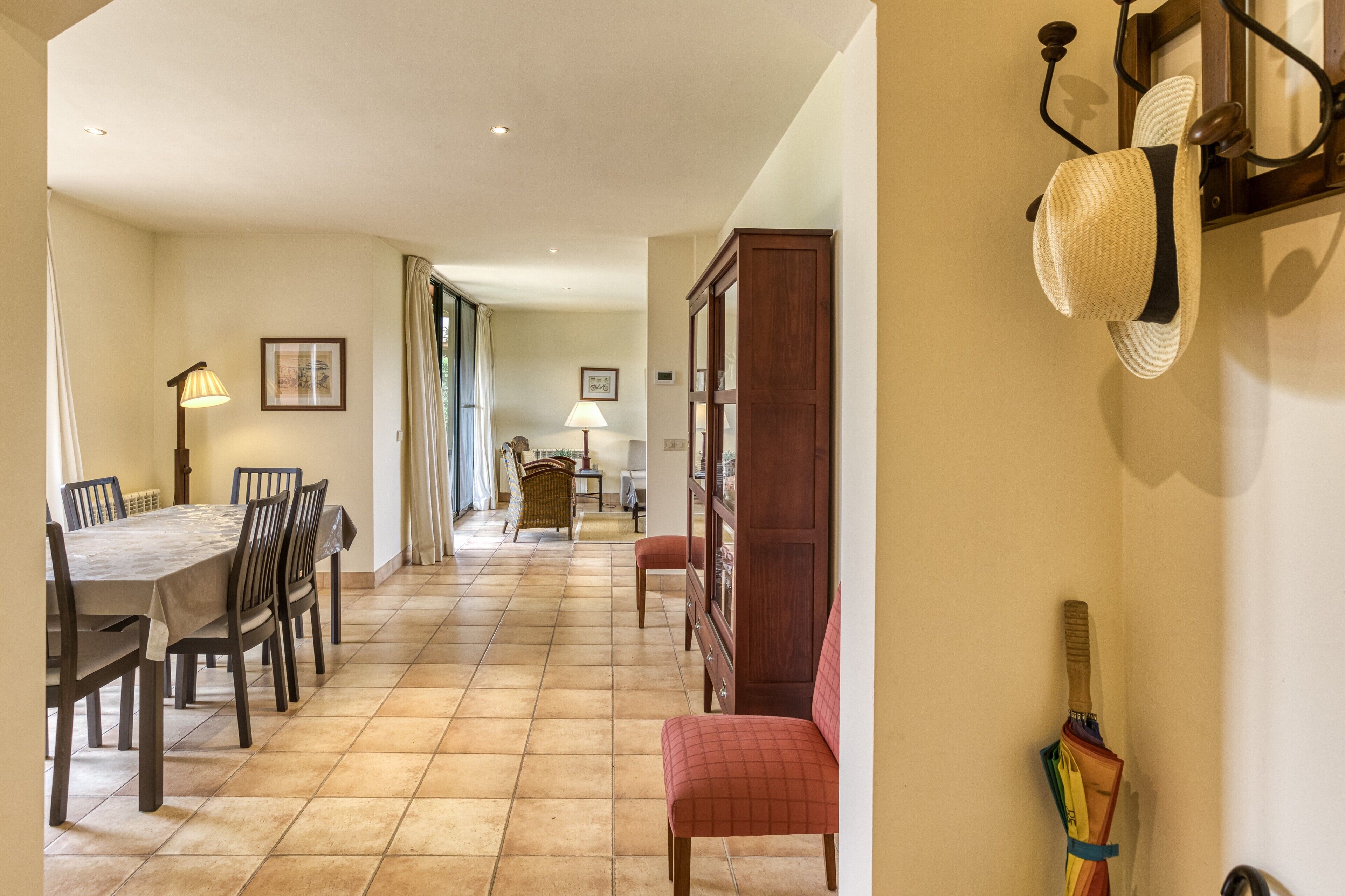 A dining area with a table and chairs, a lamp, a cabinet, and a wall-mounted hat rack.