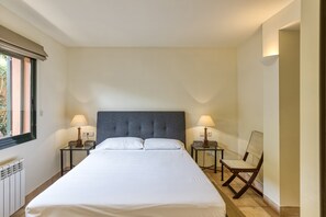 Een hotelkamer met een groot bed, twee nachtkastjes met lampen, een stoel en een raam.