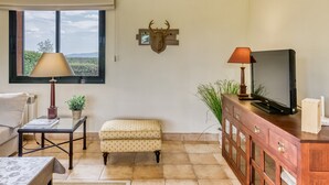 A living room with a sofa, a coffee table, a television on a wooden cabinet, a lamp, and a wall-mounted deer head. - Holiday Home 'Josi' with Shared Pool, Private Terrace and Wi-Fi (Navata)