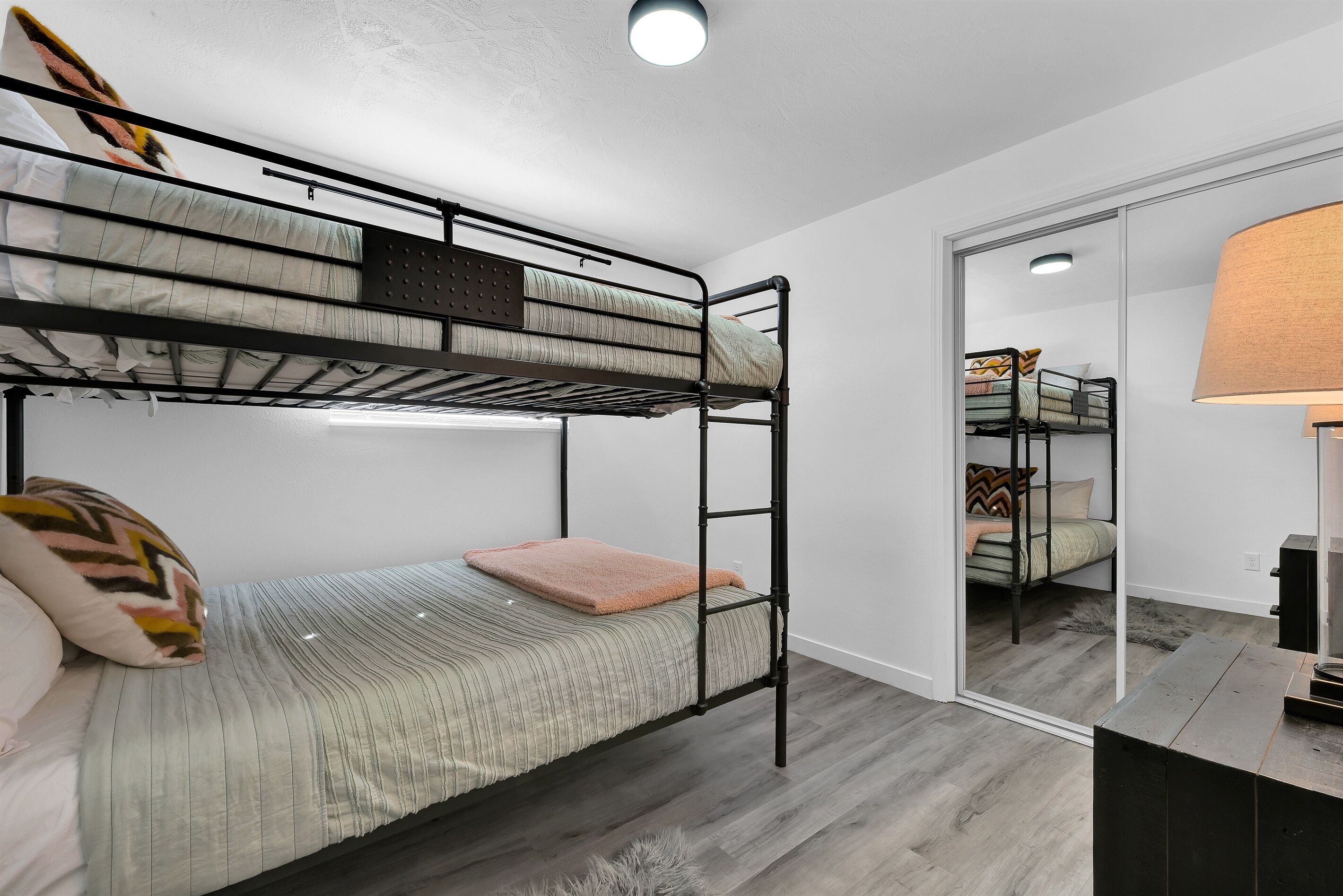 A bunk bed room with a mirror and a lamp.