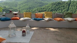 A rooftop seating area with a view of a forested hill, white lanterns, and colorful cushions. - Farmhouse "Parulia Country House - Gea" with Shared Pool, Shared Terrace & Wi-Fi (Molin Nuovo)