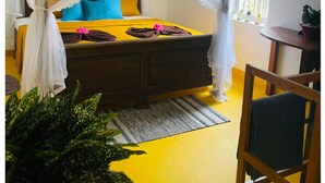 A bed with a canopy, a bedside table, a chair, and a window with a view of greenery. - Birdsong Villa, Private and Peaceful Retreat (Rathgama)
