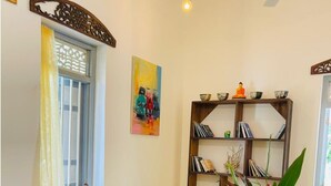 A living room with a black sofa, a wooden bookshelf, and a yellow floor. - Birdsong Villa, Private and Peaceful Retreat (Rathgama)