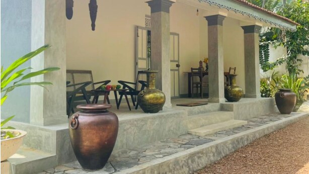 A covered outdoor seating area with stone steps, two large vases, and a table with chairs. - Birdsong Villa, Private and Peaceful Retreat (Rathgama)