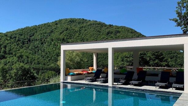 A swimming pool with lounge chairs and a covered seating area, surrounded by a forested hillside. - Farmhouse "Parulia Country House - Estia" with Shared Pool, Shared Terrace & Wi-Fi (Molin Nuovo)