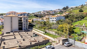 Zona residencial con estacionamiento, un pequeño edificio y casas con tejados rojos.