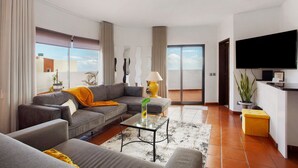 Una sala moderna con sofá, una mesa de centro, televisor y un balcón con vistas.