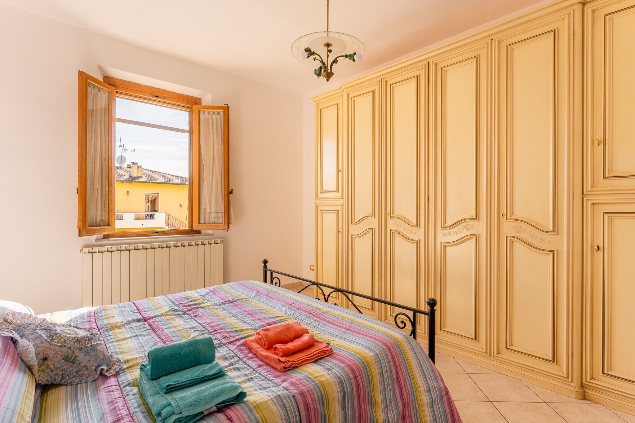 Une chambre à coucher avec un lit, une fenêtre, un radiateur et une armoire.