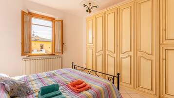 Une chambre à coucher avec un lit, une fenêtre, un radiateur et une armoire.