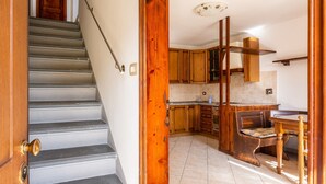 A staircase leading to a kitchen with wooden cabinets and a dining area. - Holiday Home 'Enza's Petite Maison' with Wi-Fi (Staffoli)