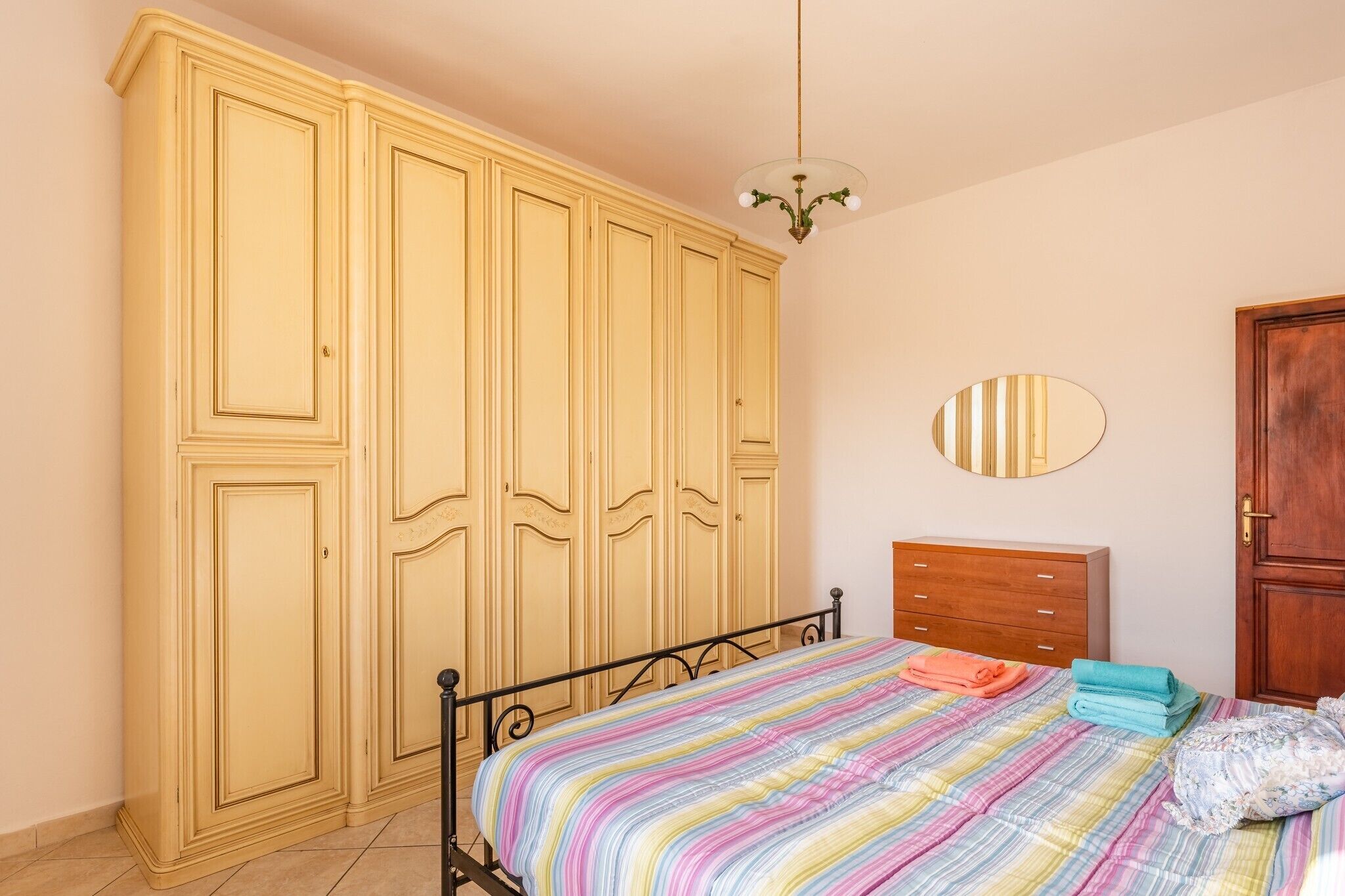 Ein Schlafzimmer mit Bett, Kleiderschrank, Kommode und Spiegel.