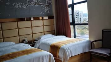 A hotel room with two beds, a wooden headboard, a window with a view, and a chair.