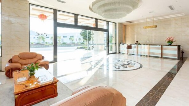 A hotel lobby with a reception desk, a seating area with a sofa and a coffee table, and large windows offering a view of the outside. - Xuangui Hotel (Guiding)