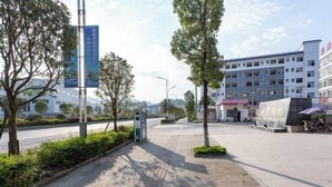 A pedestrian walkway with trees and a building in the background. - Xuangui Hotel (Guiding)