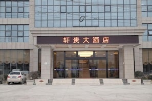 A hotel entrance with a signboard, a car parked in front, and a clear view of the building's facade. - Xuangui Hotel (Guiding)