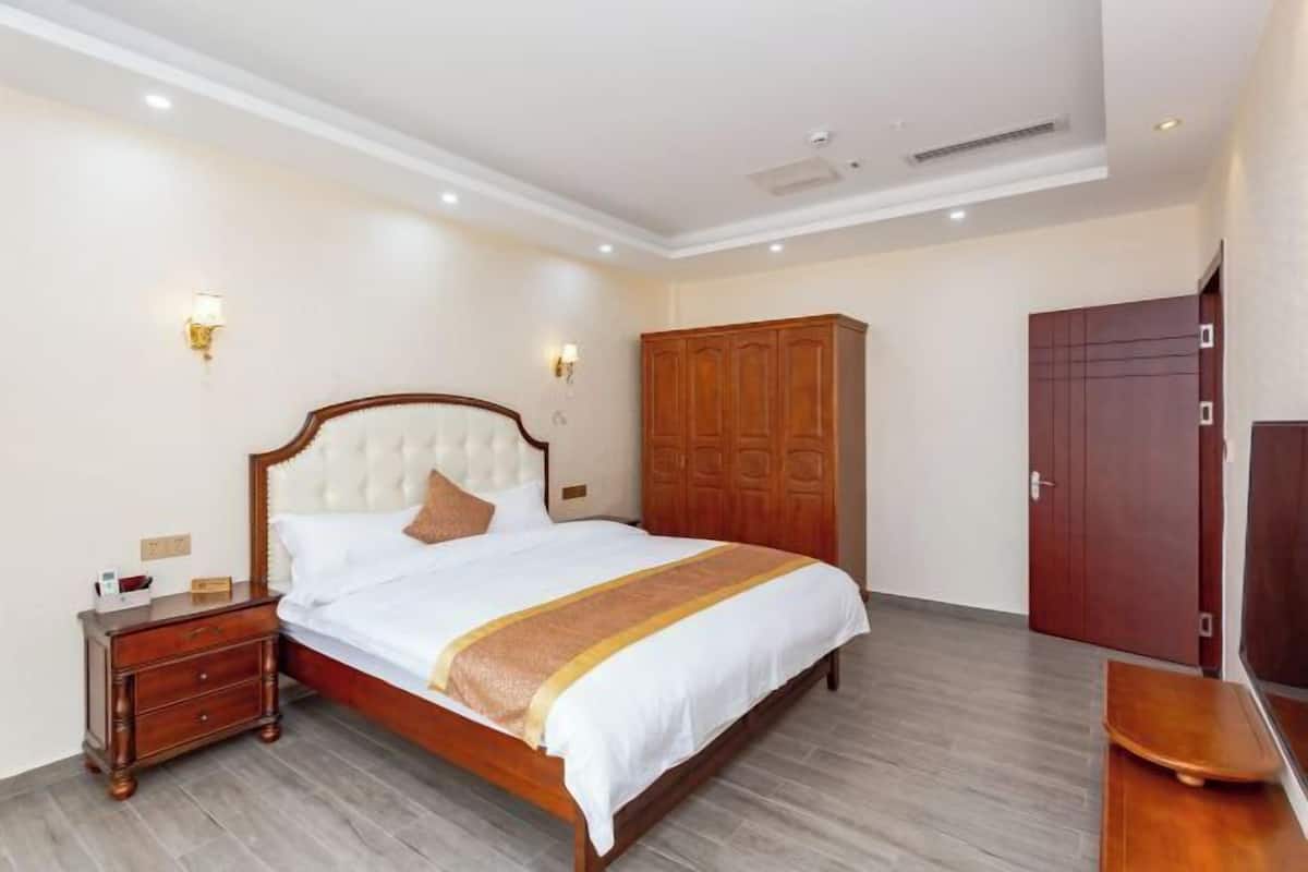 A hotel room with a large bed, wooden wardrobe, and a nightstand.