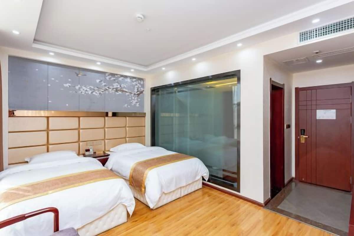 A hotel room with two beds, a large window, and a wooden floor.