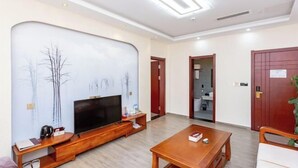 A modern living room with a flat-screen TV, wooden furniture, and a large wall mural. - Xuangui Hotel (Guiding)