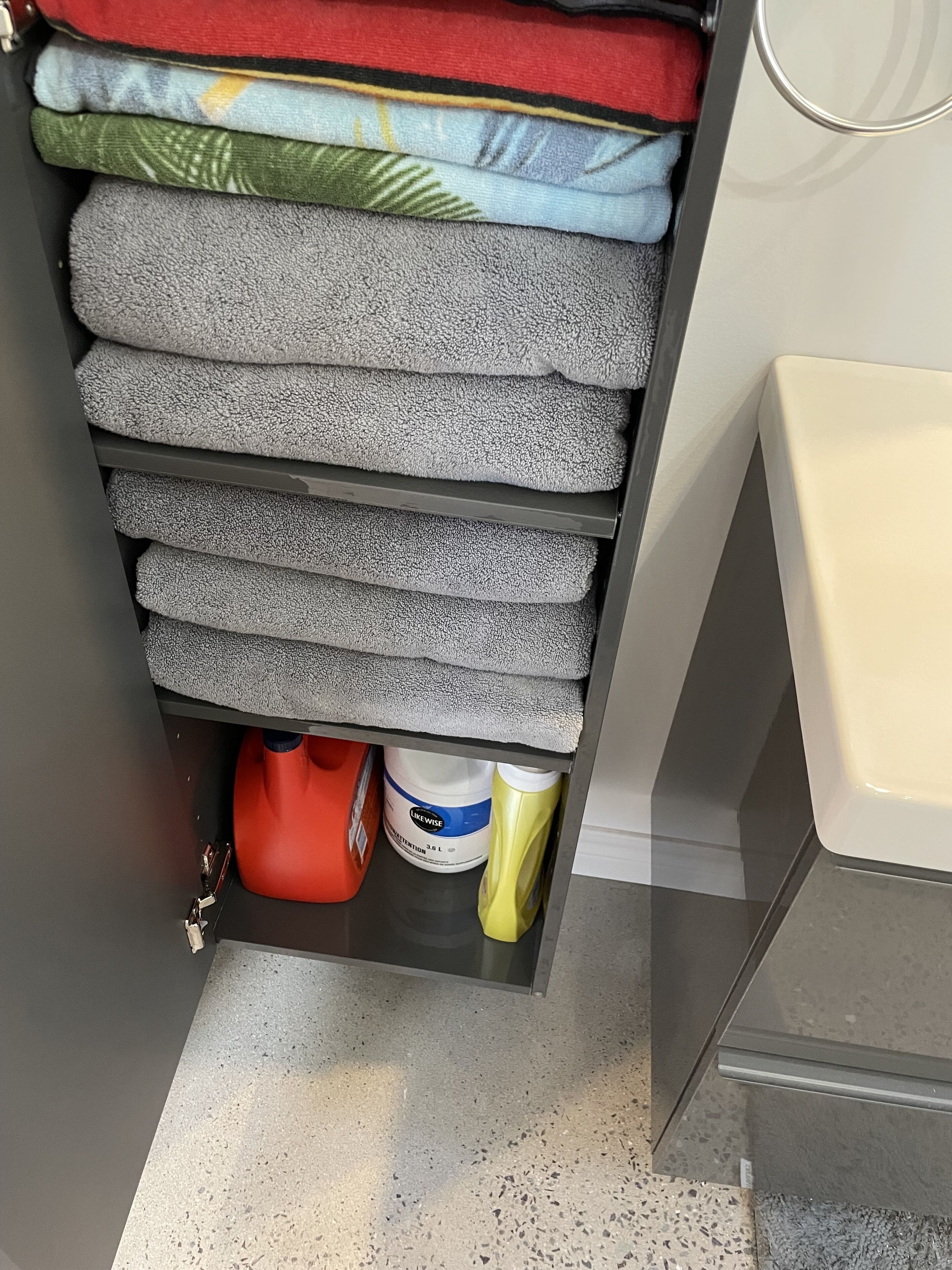 Un espace de rangement où les serviettes et les produits de nettoyage sont soigneusement rangés.