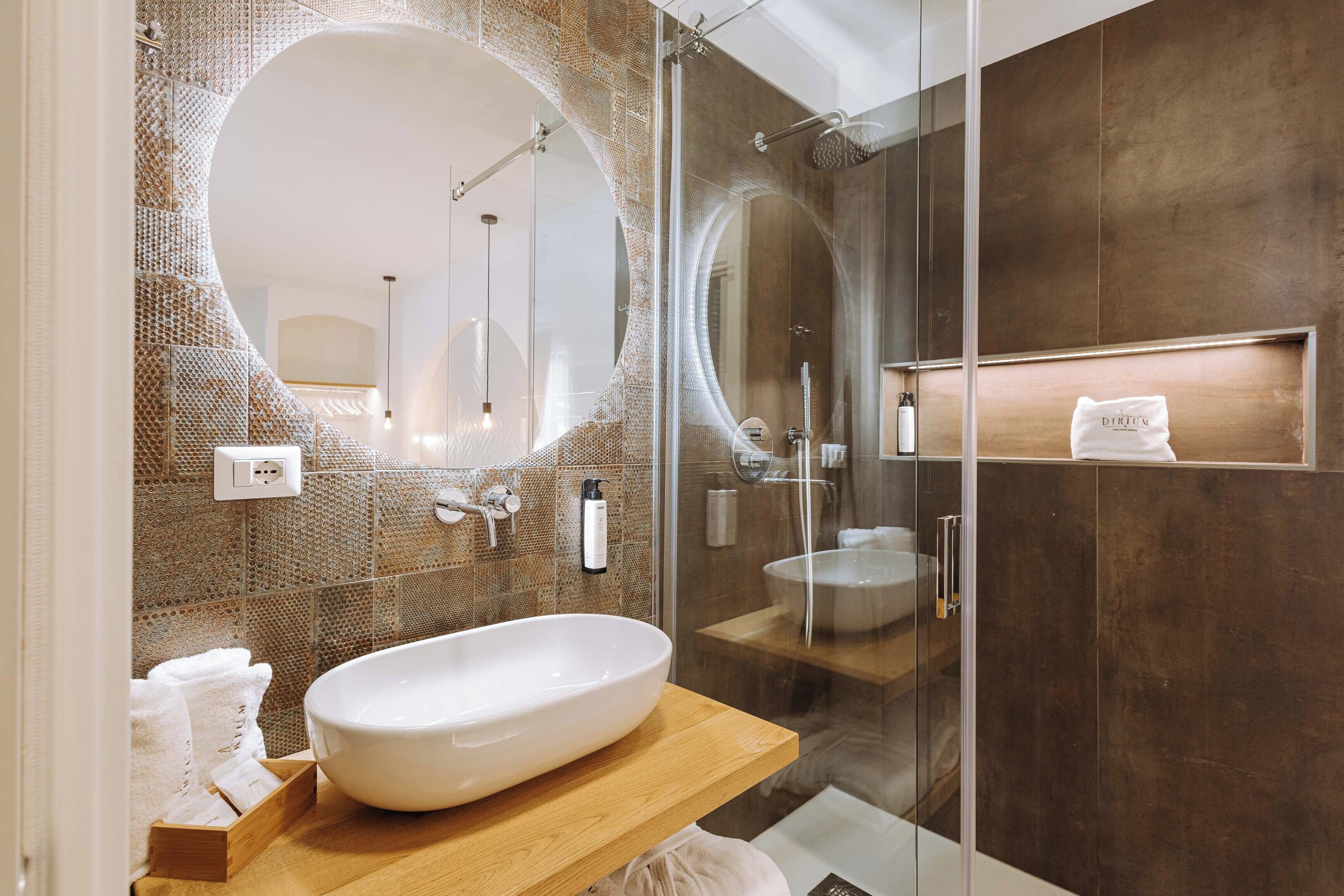 A modern bathroom with a large oval sink, a glass-enclosed shower, and a large mirror.