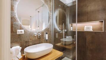 A modern bathroom with a large oval sink, a glass-enclosed shower, and a large mirror.