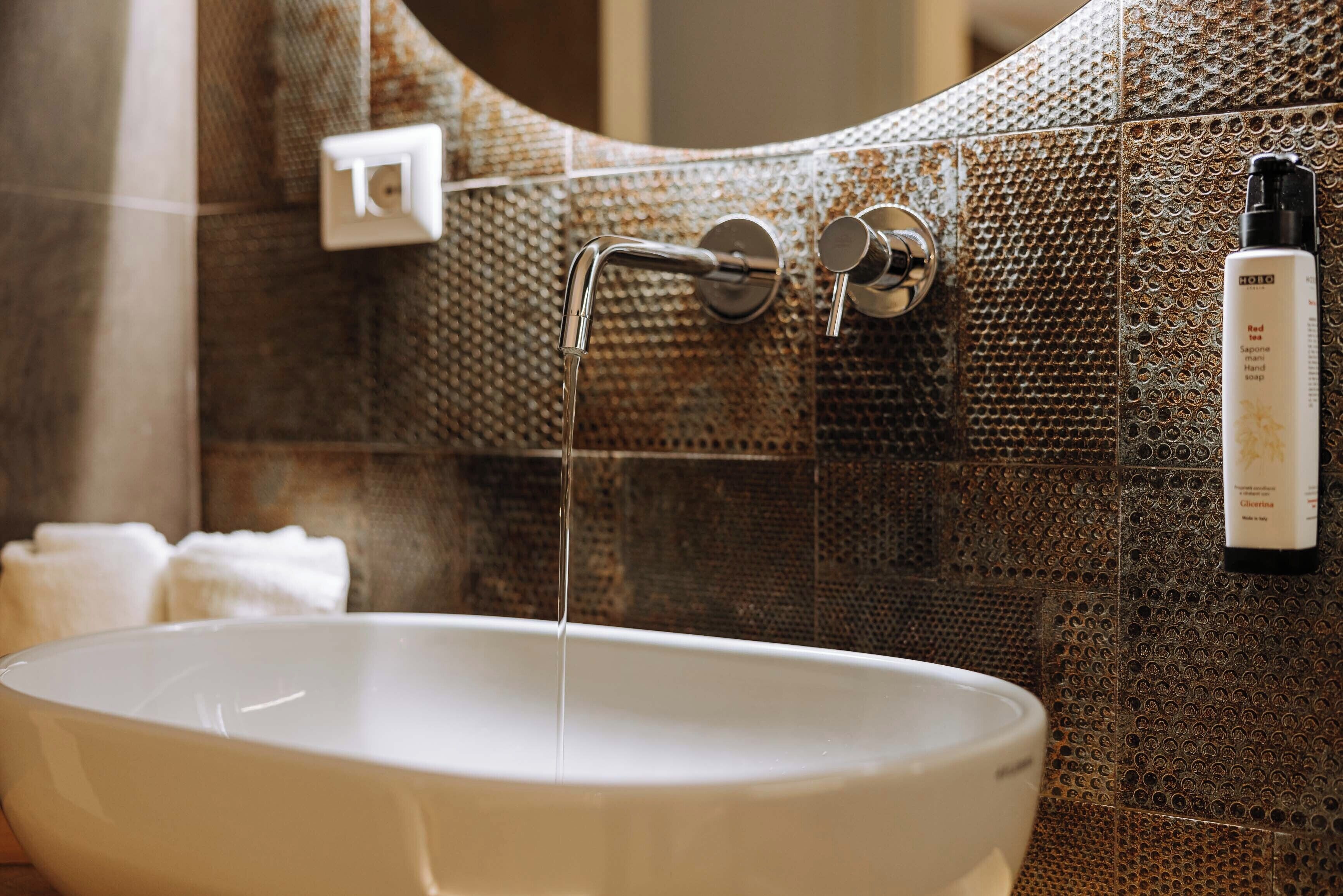 A bathroom with a white sink, a mirror, and a textured wall.