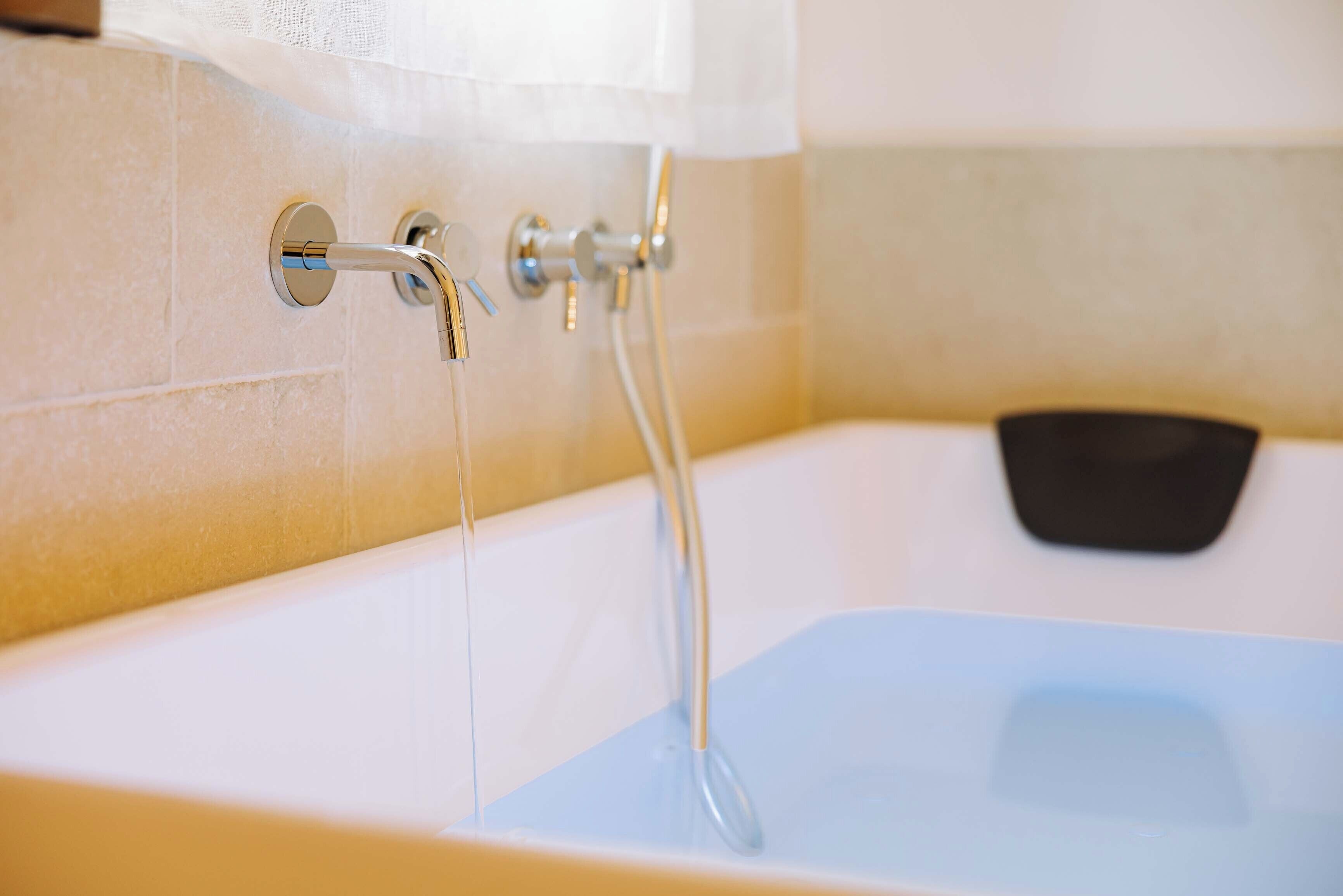 Una bañera con grifo y ducha de mano.