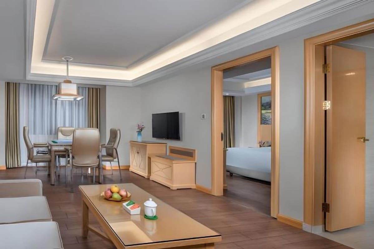 Een hotelkamer met een houten salontafel, een televisie, een bed en een bureau.