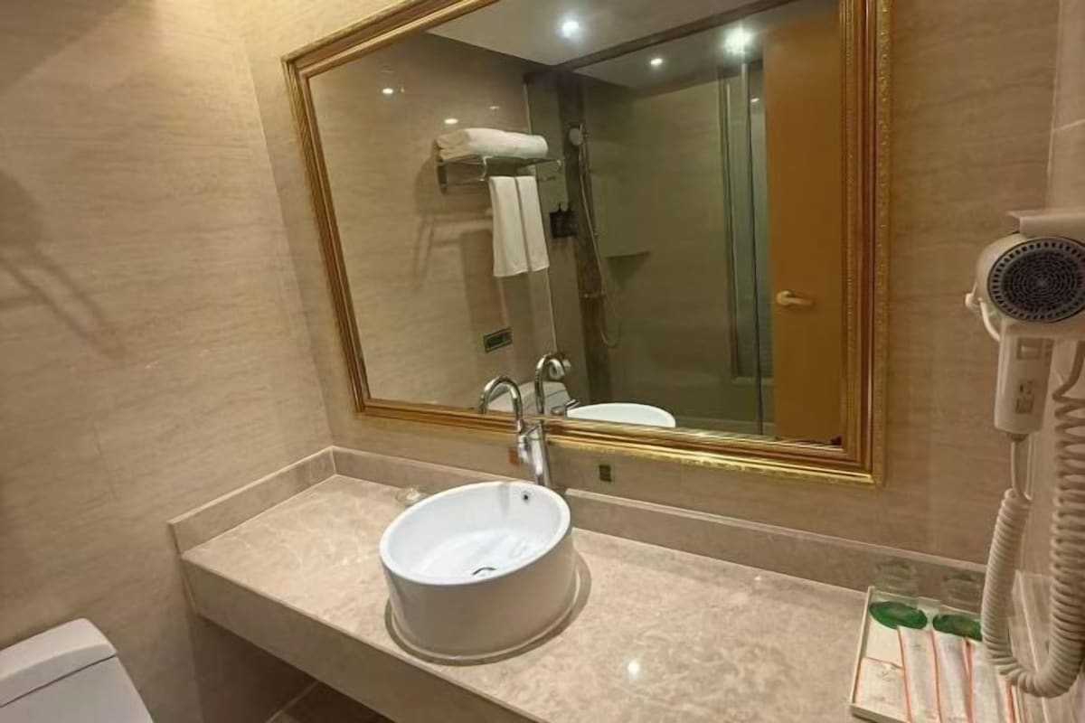 Een badkamer met een wastafel, spiegel, douche en haardroger.