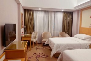 Een hotelkamer met twee bedden, een bureau met stoel, een televisie en een groot raam met gordijnen.