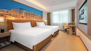 A hotel room with two beds, a desk, a chair, and a large window. - Vienna Hotel (Huidong Jilong) (Huidong)