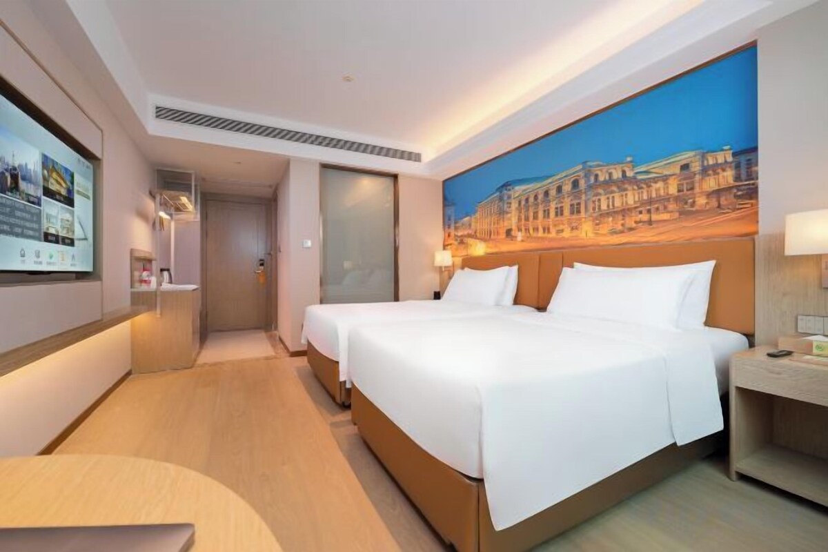 A hotel room with a large bed, a desk, a TV, and a painting on the wall.
