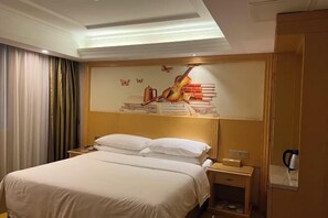 Een hotelkamer met een bed, nachtkastje, koffiezetapparaat en een wanddecoratie van een viool en boeken.
