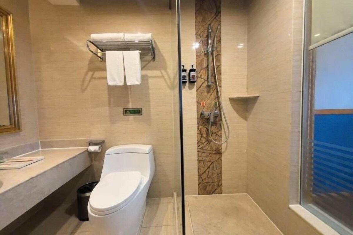 A modern bathroom with a glass-enclosed shower, a white toilet, a towel rack, and a marble wall.