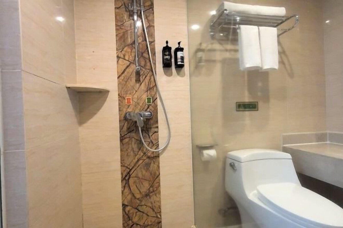 A bathroom with a shower, toilet, and towel rack.