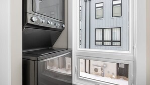 Eine Küche mit Herd und Backofen, ein Fenster mit Blick auf ein Gebäude und eine Tür.