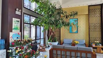 A lobby with a large plant, seating area, and decorative wall art.