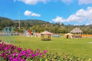 A grassy field with playground equipment, tents, and a clear sky.