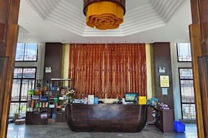 A reception area with a wooden reception desk, a large vertical curtain, and a chandelier. - Gaofu Linyuan Hotel (Yao'an)