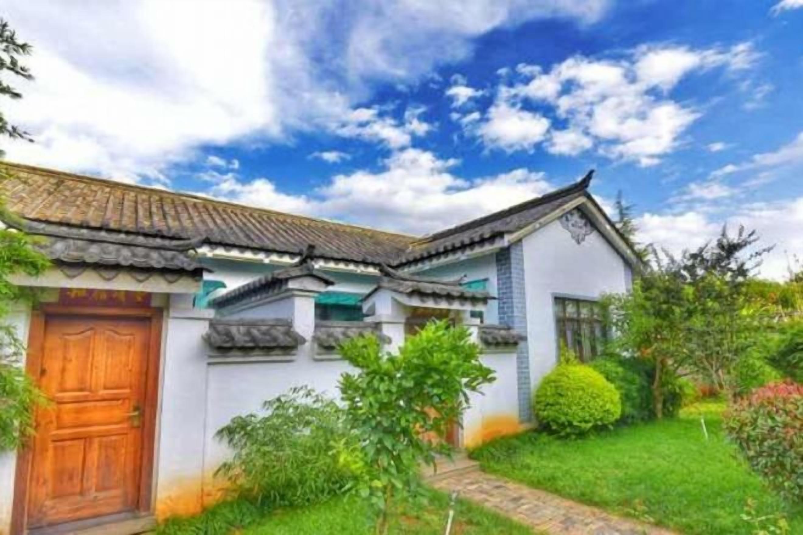 A traditional building with a tiled roof, a wooden door, and a well-maintained garden.