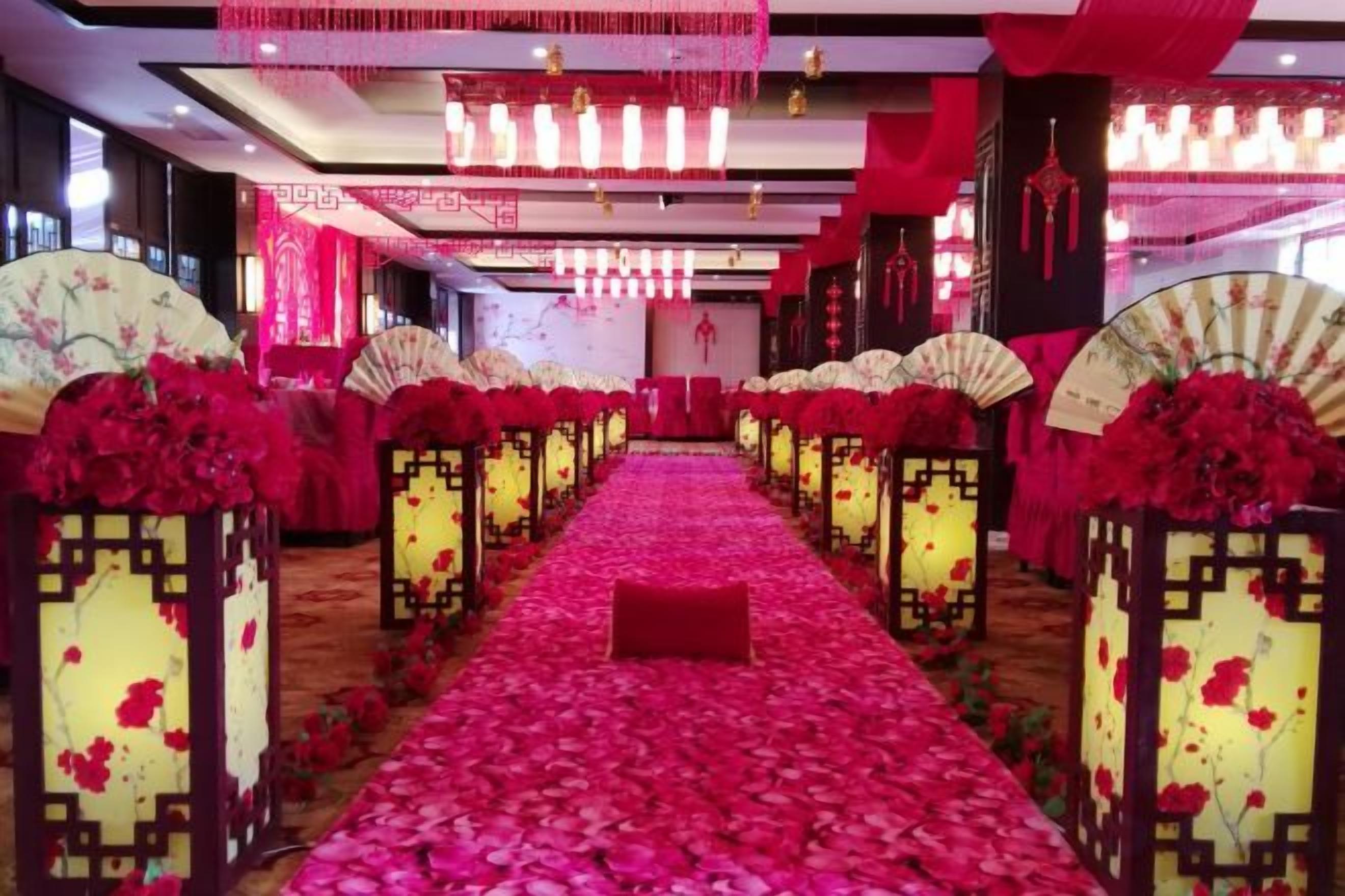 A corridor with a red carpet, traditional Chinese fans, and red flowers.