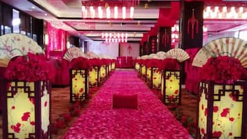 A corridor with a red carpet, traditional Chinese fans, and red flowers.