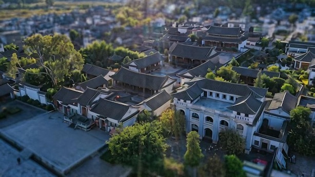 Vue aérienne d’une ville traditionnelle, avec ses bâtiments historiques, sa place centrale et la verdure qui l’entoure.