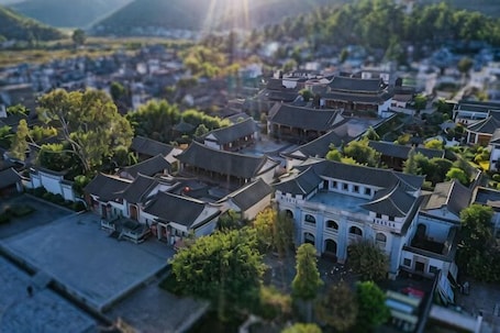 An aerial view of a traditional town with historic buildings, a central square, and surrounding greenery.. Gaofu Linyuan Hotel