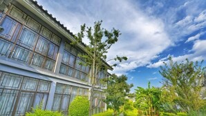 Un hôtel au design moderne, doté de grandes fenêtres et d’un jardin bien entretenu, agrémenté de diverses plantes et d’un sentier.